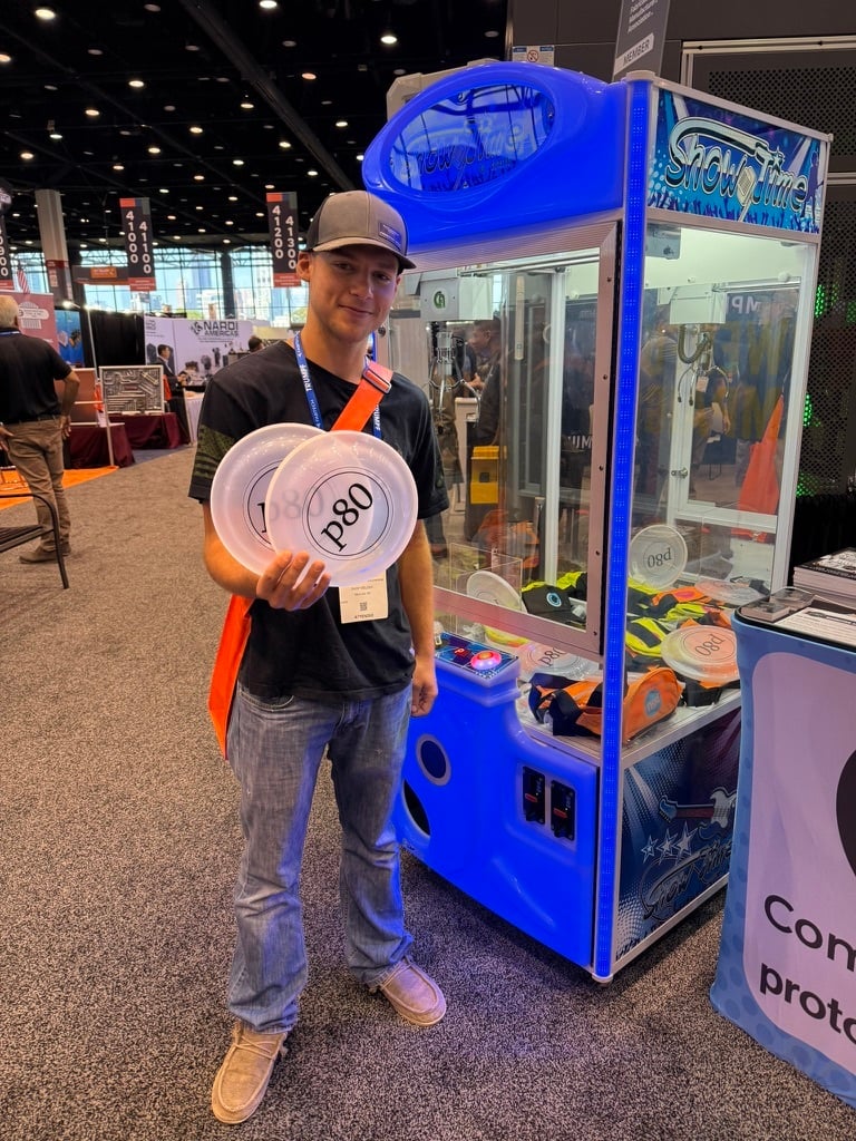trade show attendee in front of claw machine with a prize