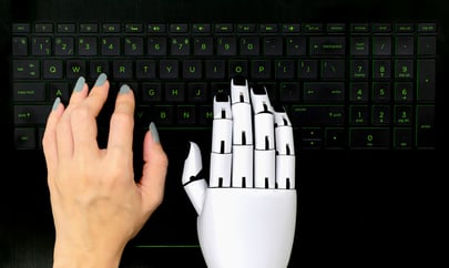 AI in b2b marketing - human hand typing next to robotic hand