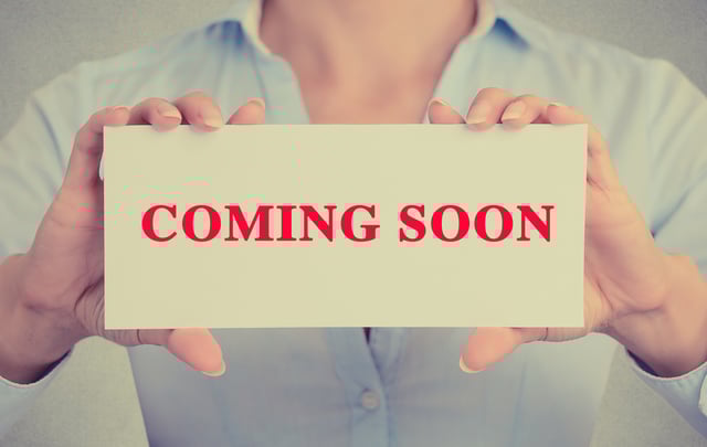 inbound marketing plan for new products - Businesswoman holding sign with "coming soon" on it